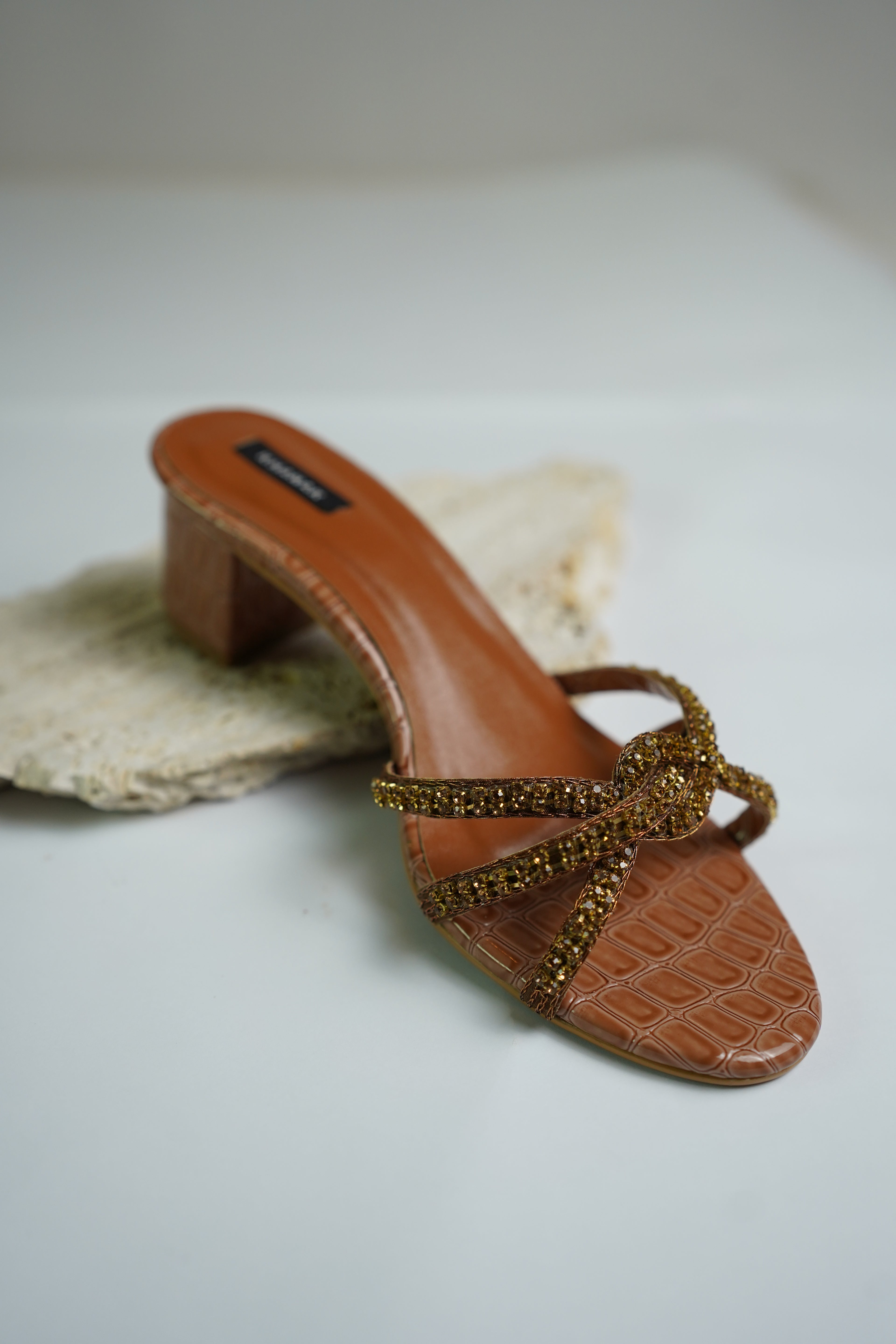 Brown sandal with gold straps on a white background